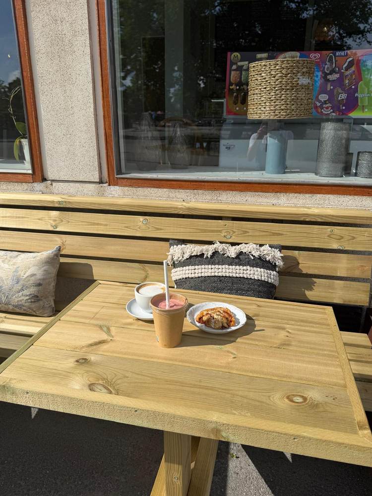 Kaffe, smoothie och kanelbulle på ett bord på uteserveringen
